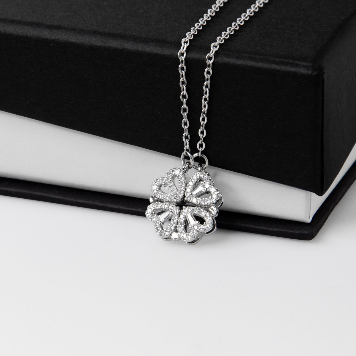 Clover pendant draped over a black gift box | Magnetic Hearts Necklace