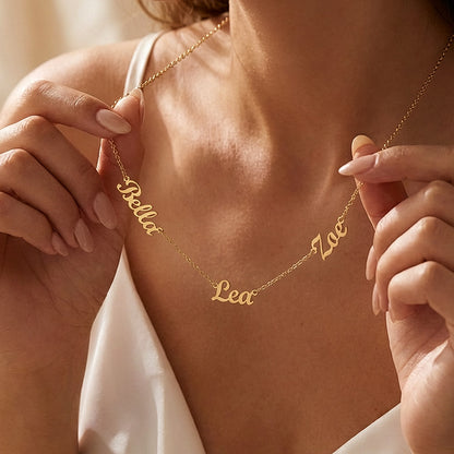 Woman holding the gold finish three-name necklace at her neckline | Multiple Name Necklace