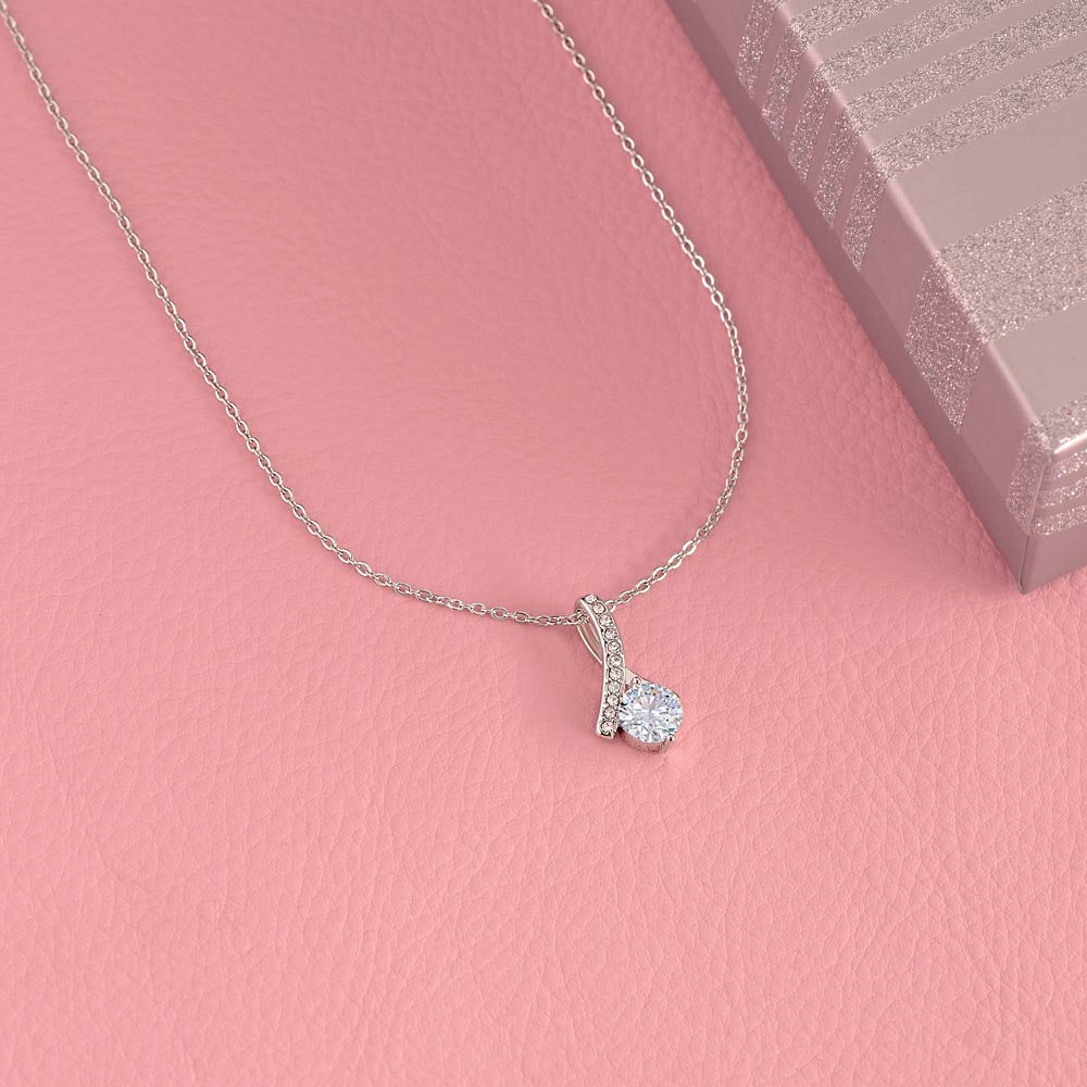 White gold finish pendant on a pink background beside its box | Proud Mom Necklace