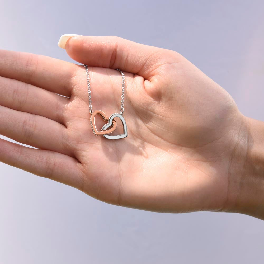 Open hand holding the steel and rose gold interlocking hearts pendant | Always Proud, Always Loved Necklace