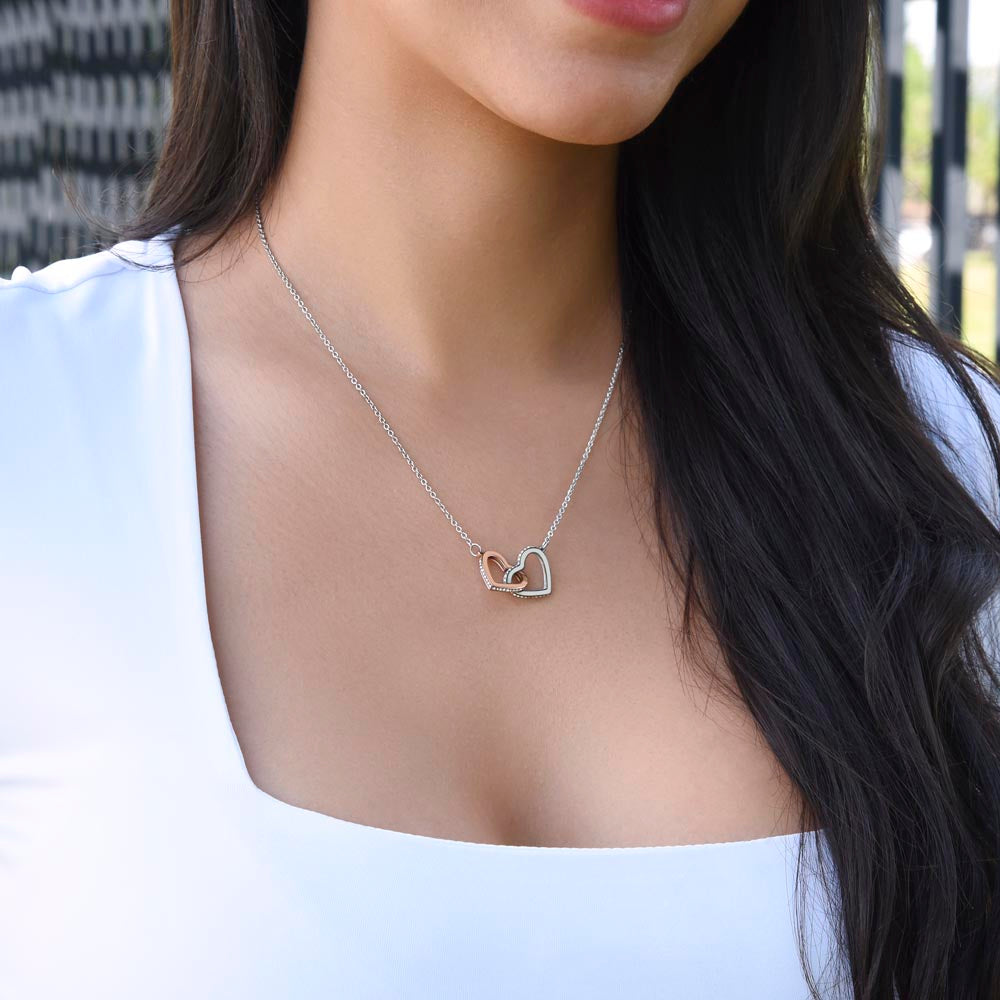 Woman in a white top wearing the steel and rose gold interlocking hearts | Always Proud, Always Loved Necklace