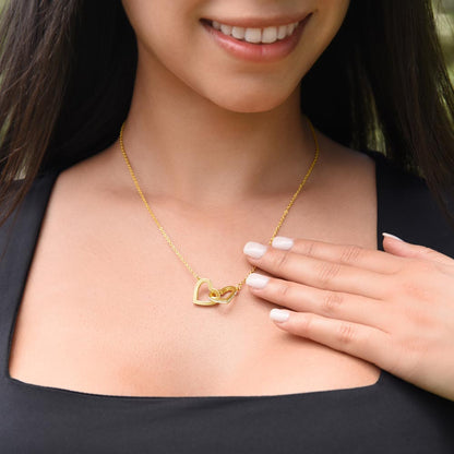 Smiling woman touching the yellow gold finish hearts pendant | Interlocking Hearts Necklace