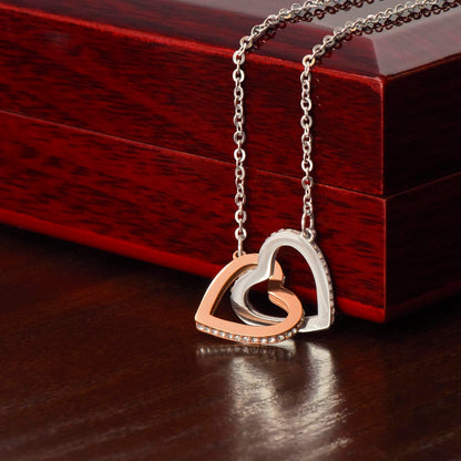 Steel and rose gold hearts draped over the mahogany Luxury Box | Interlocking Hearts Necklace