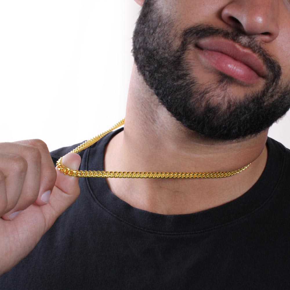 Man holding the gold finish chain between his fingers | Cuban Link Chain