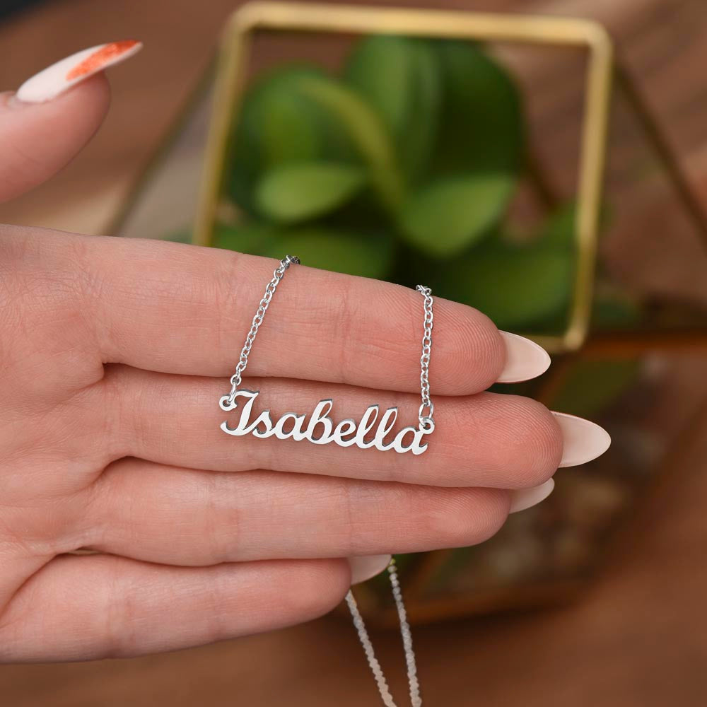 Silver name necklace held over a plant | Chosen Name Necklace