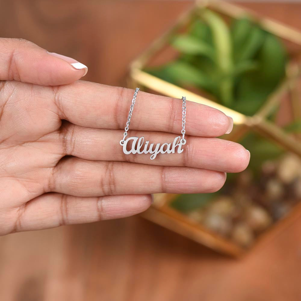 Silver name necklace held over a plant | Chosen Name Necklace