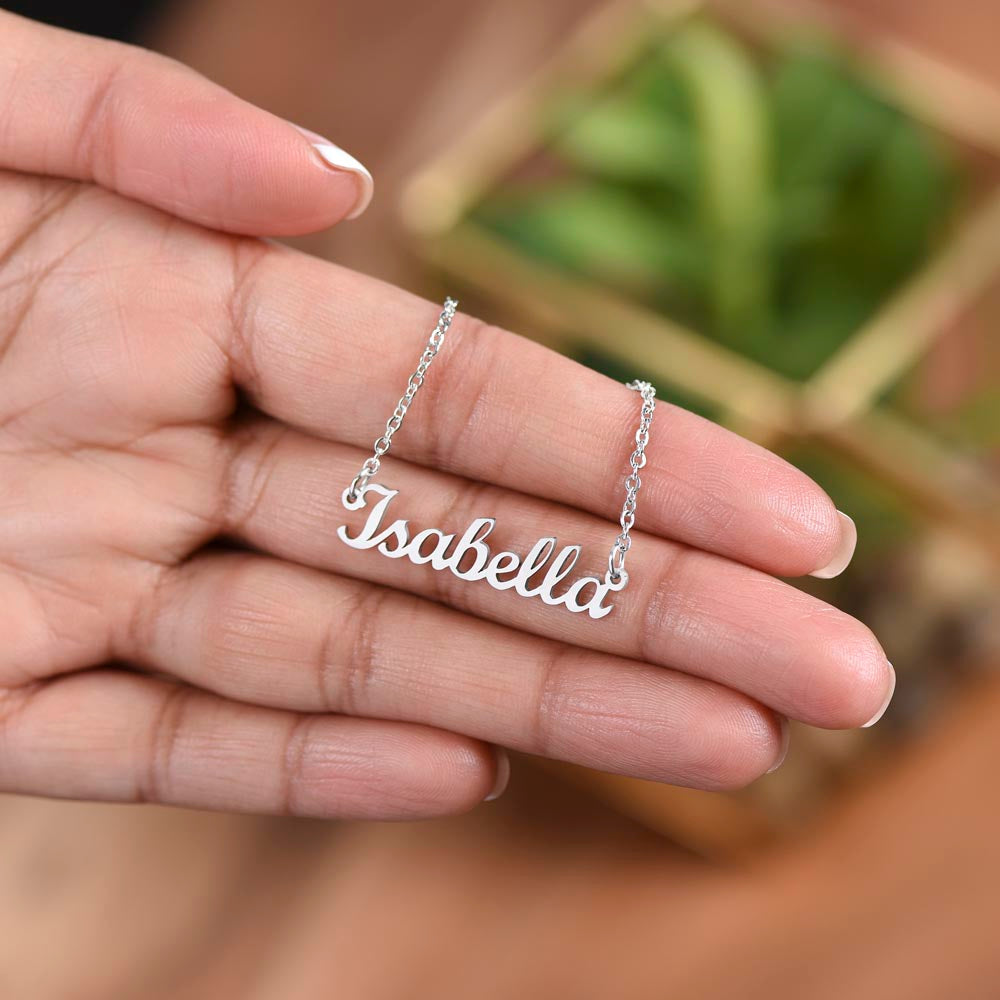 Silver name necklace held over a plant | Chosen Name Necklace