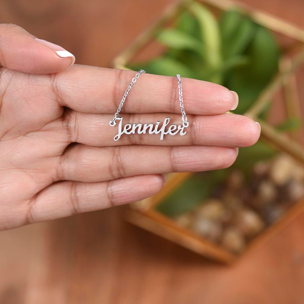 Silver name necklace held over a plant, close-up | Chosen Name Necklace