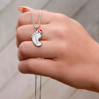 Silver baby feet charm held between the fingers | Baby Feet Birthstone Necklace