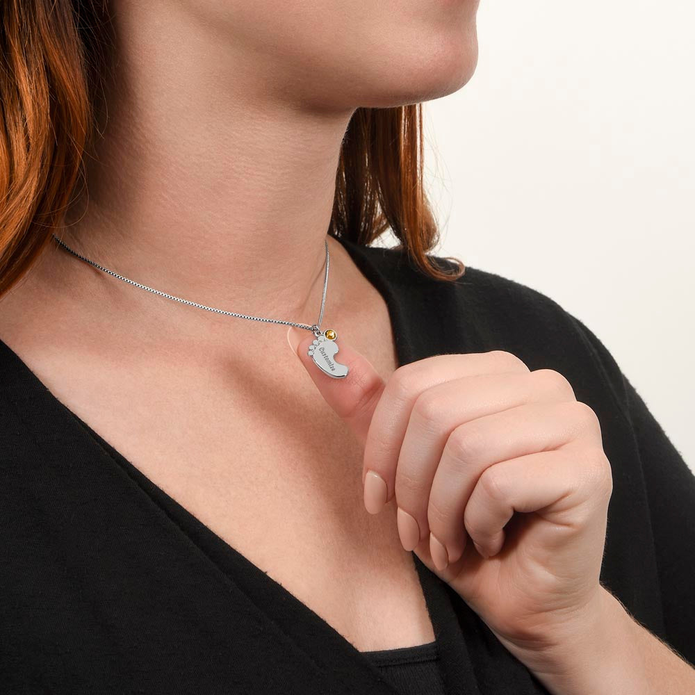 Silver baby feet necklace worn, hand at the collar | Baby Feet Birthstone Necklace