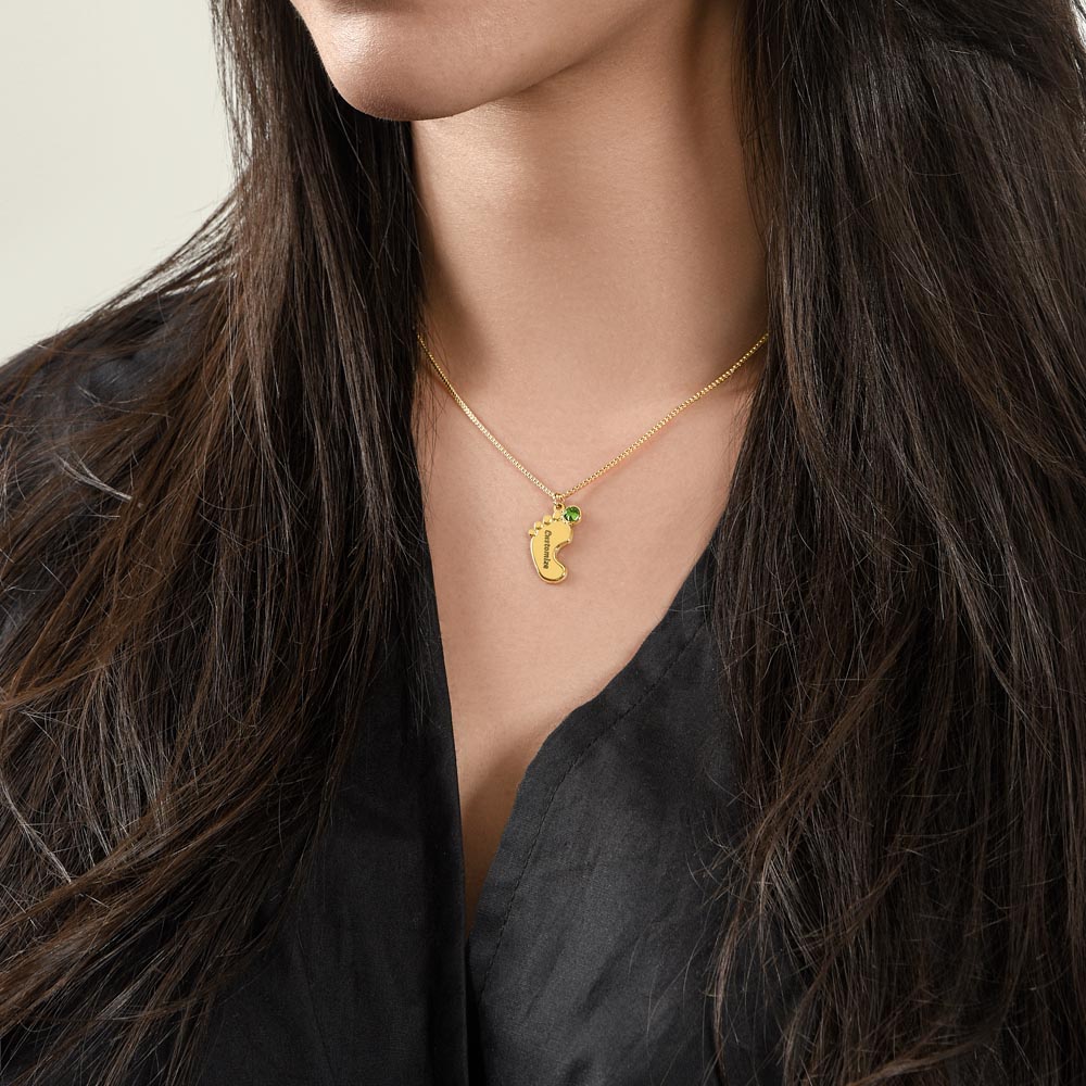 Gold finish baby feet necklace worn with a black top | Baby Feet Birthstone Necklace