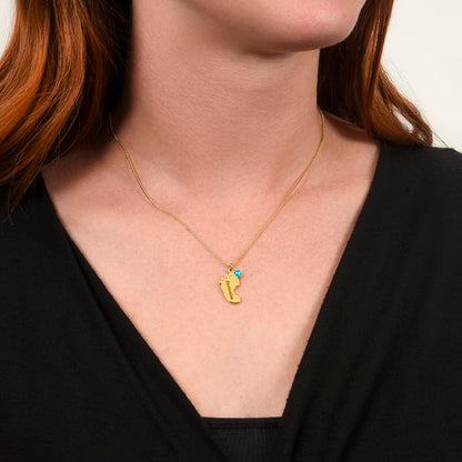 Gold finish baby feet necklace worn with a black top, close-up | Baby Feet Birthstone Necklace