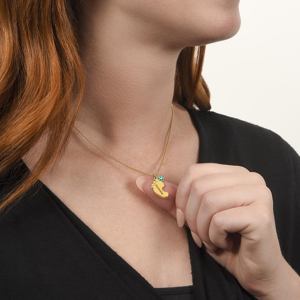 Gold finish baby feet necklace worn, hand at the pendant | Baby Feet Birthstone Necklace