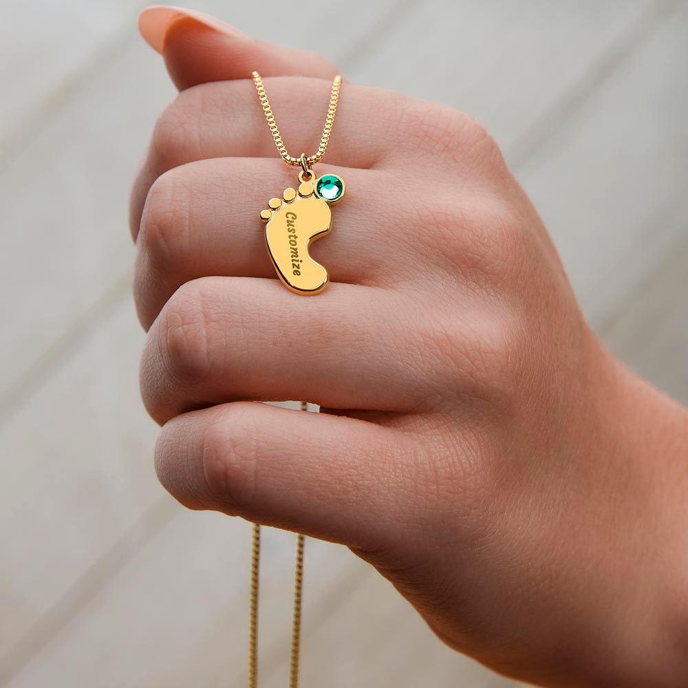 Gold finish baby feet charm held between the fingers | Baby Feet Birthstone Necklace