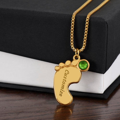 Gold finish baby feet pendant with a green birthstone on a black gift box | Baby Feet Birthstone Necklace