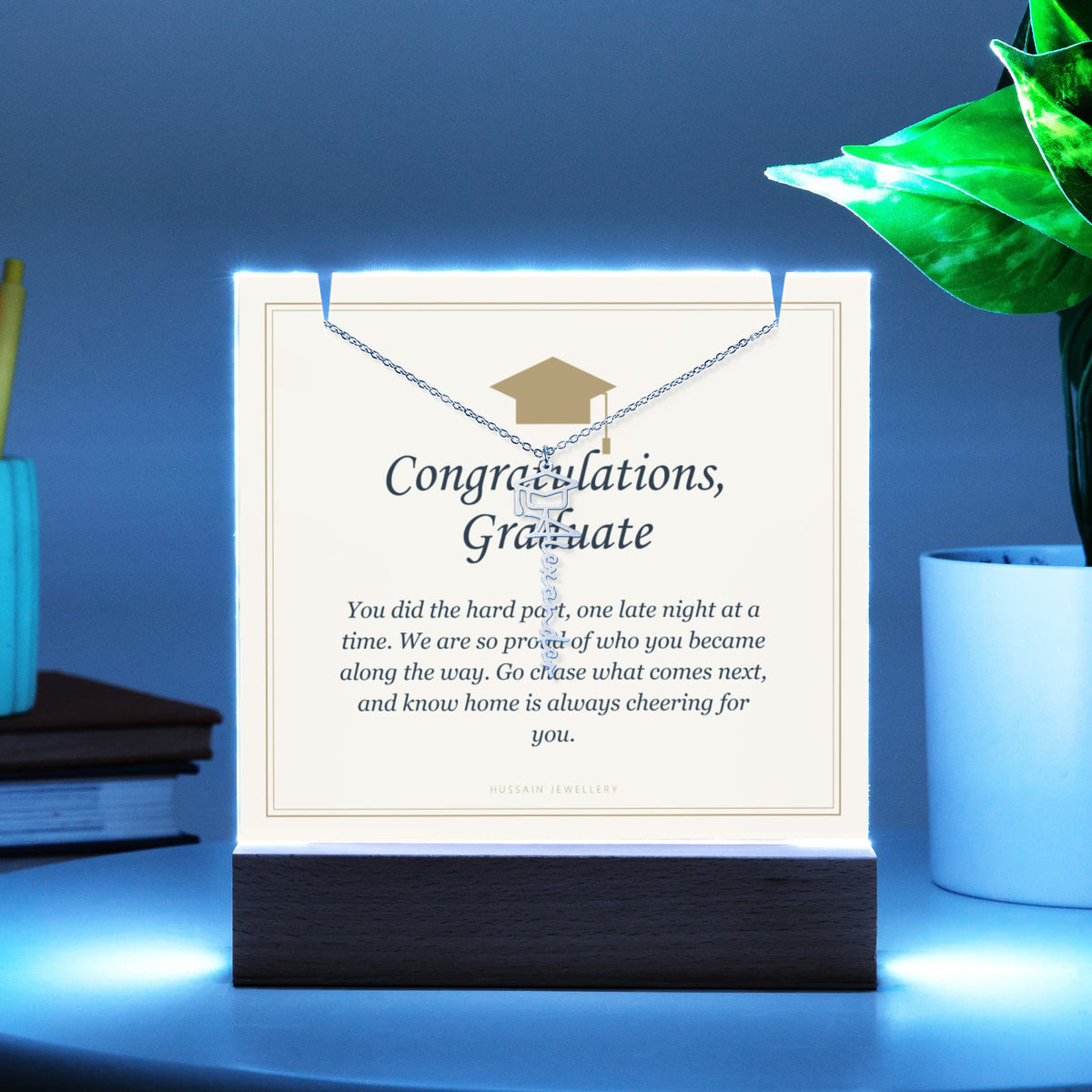 Graduate keepsake glowing blue on a desk, with the name necklace | Graduation Cap Name Necklace and Keepsake Light