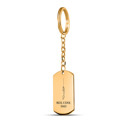 Gold tag keychain engraved with a fishing line, lure and fish and REEL COOL DAD on white