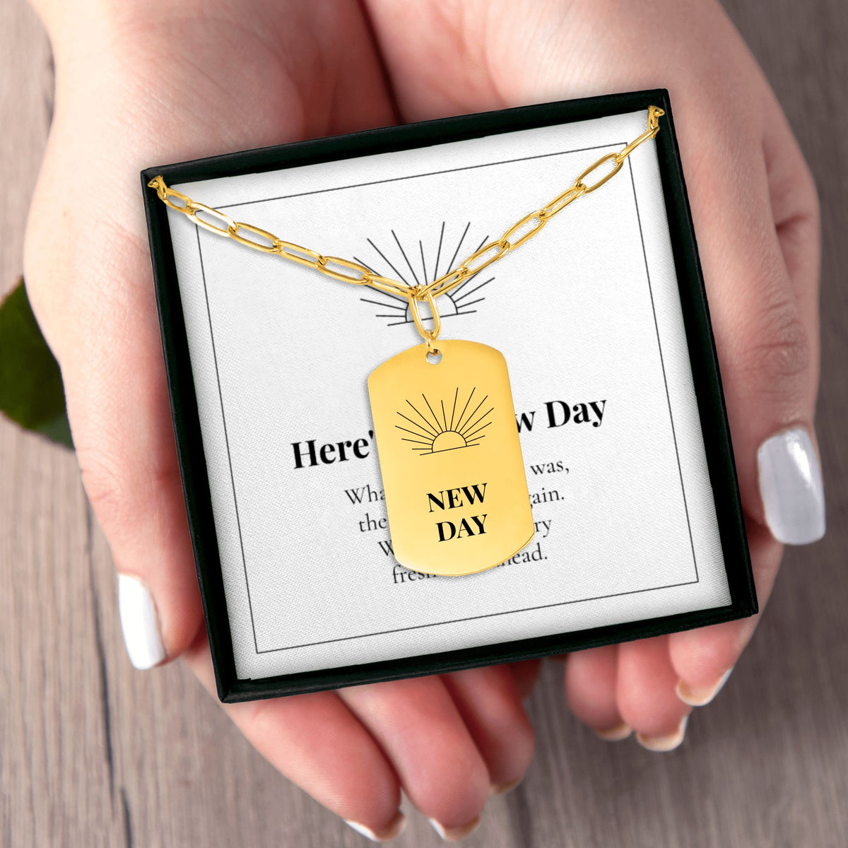 Hands holding the New Day necklace gift box