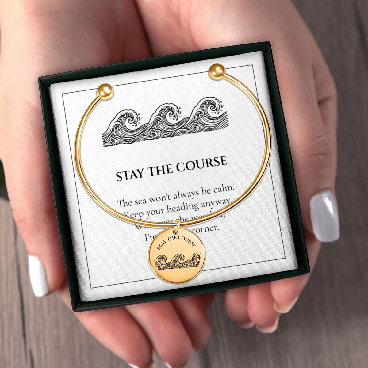 Hands holding the Stay the Course bangle gift box