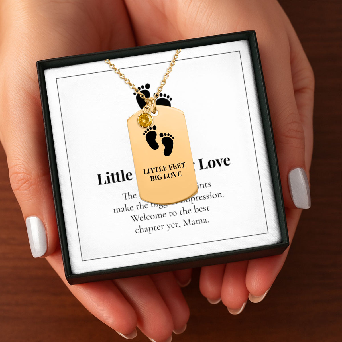 Hands holding the Little Feet, Big Love necklace gift box