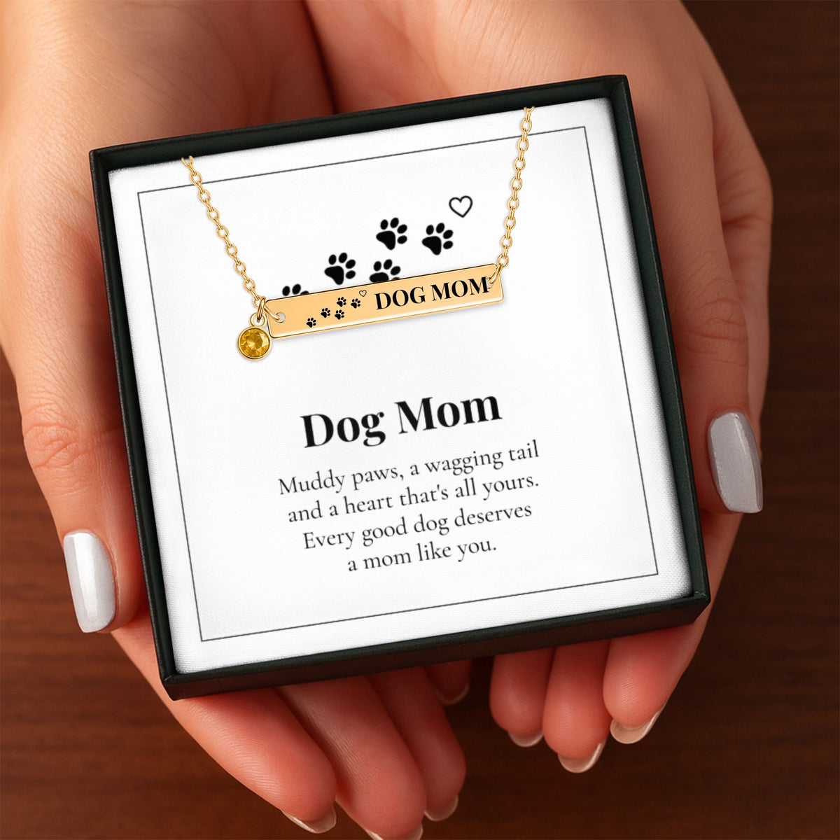 Hands holding the Dog Mom necklace gift box