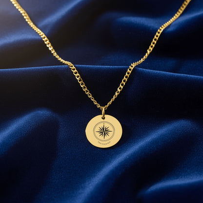 Engraved compass rose coin necklace on a Cuban chain, on navy velvet