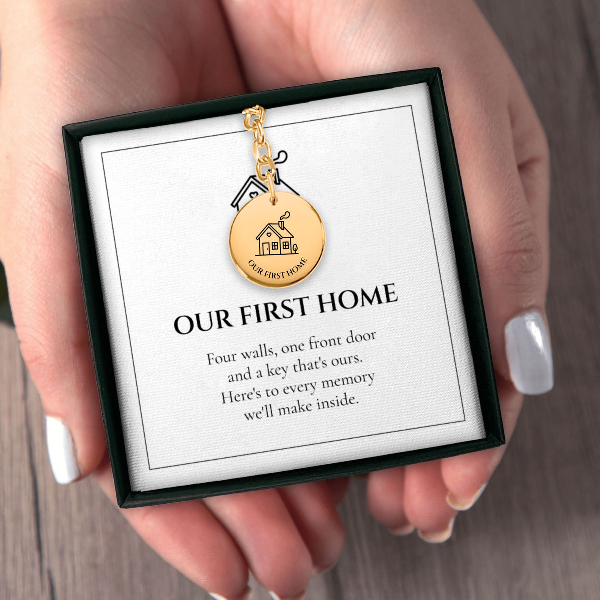 Hands holding the Our First Home keychain gift box