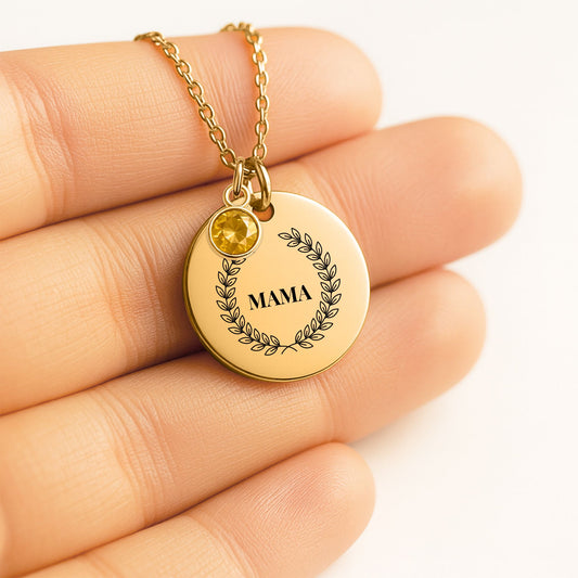 Coin pendant engraved with a laurel wreath and MAMA with a birthstone charm, held in a hand