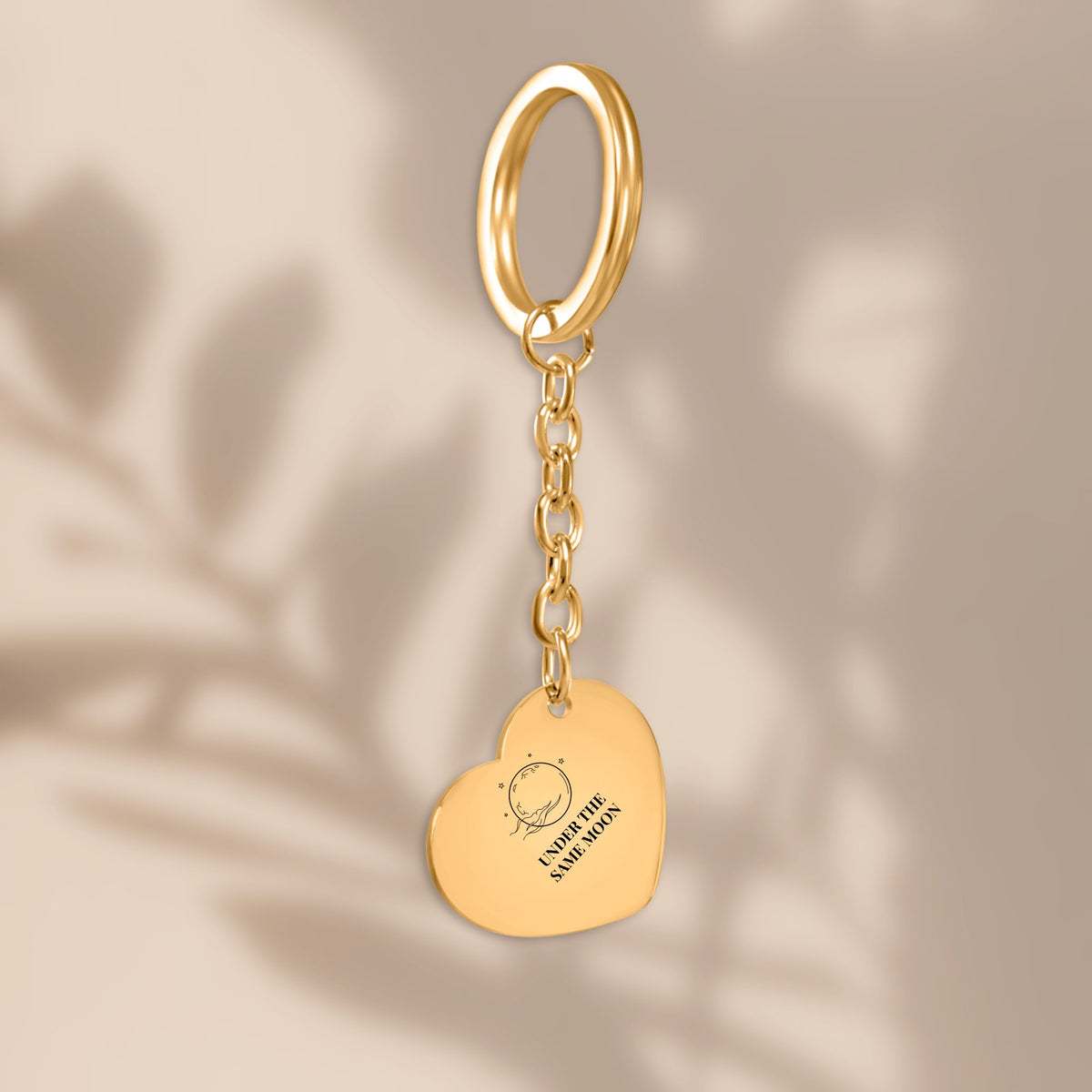 Gold heart keychain with full moon engraving in soft window light
