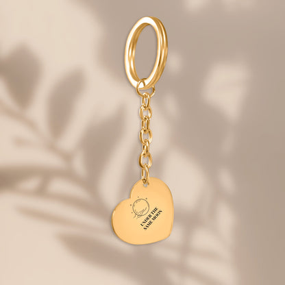 Gold heart keychain with full moon engraving in soft window light