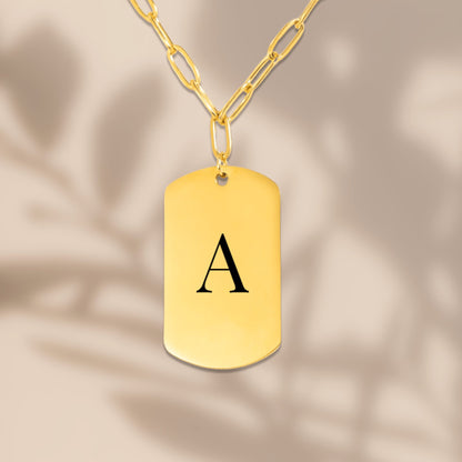 Engraved initial tag on a paperclip chain in soft window light