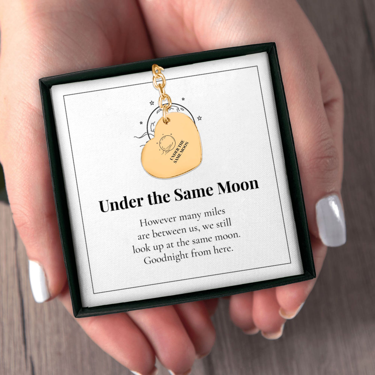 Hands holding the Under the Same Moon keychain gift box