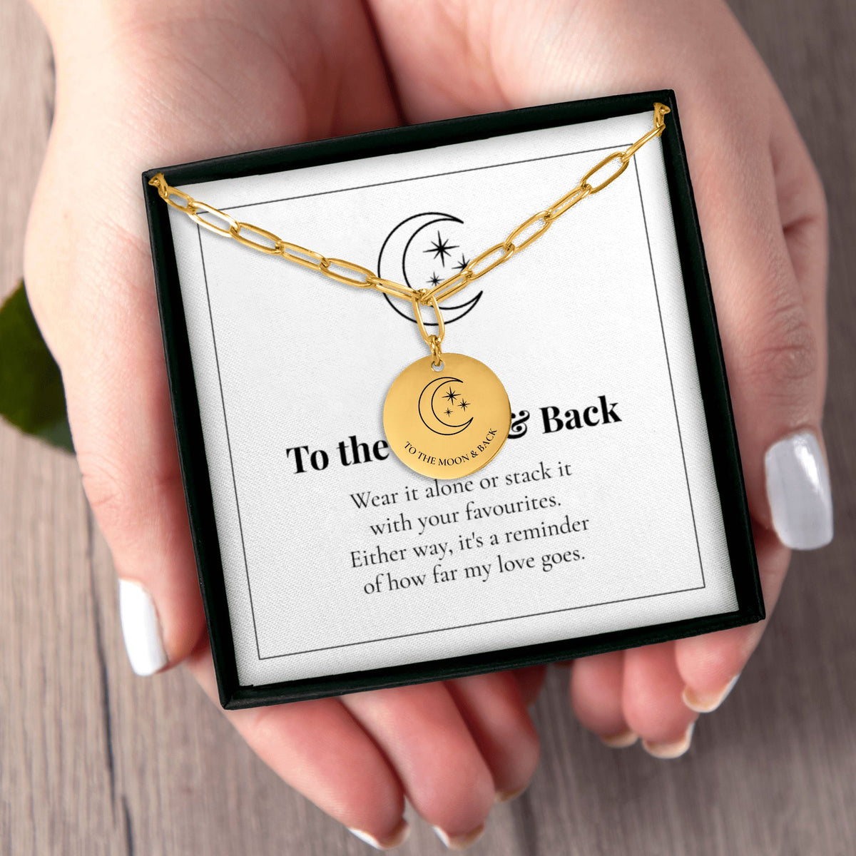 Hands holding the To the Moon and Back necklace gift box