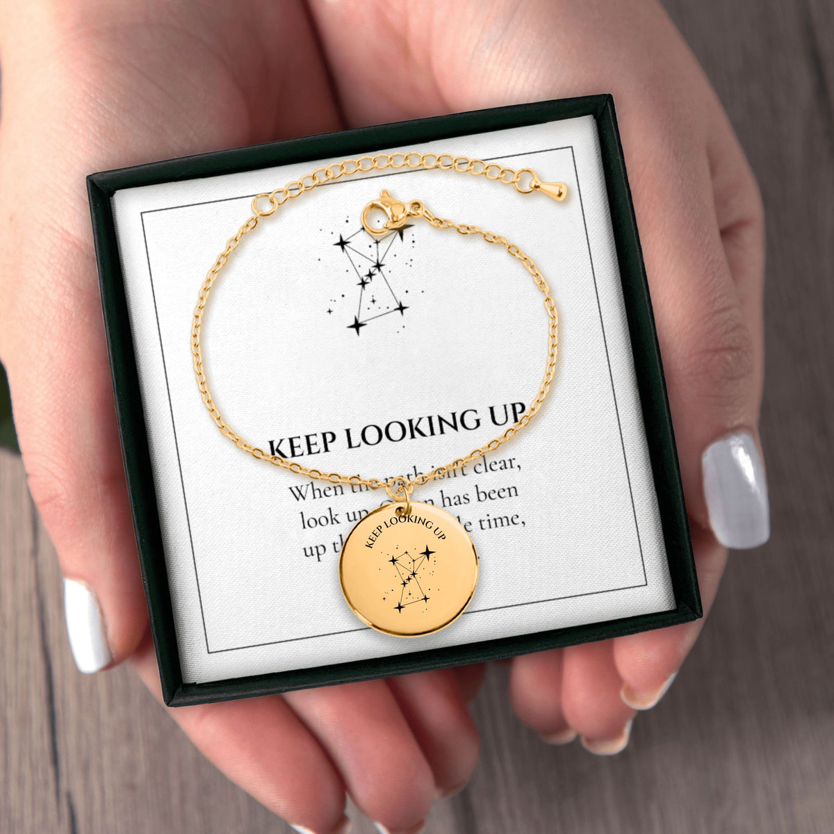 Hands holding the Keep Looking Up bracelet gift box with its message card