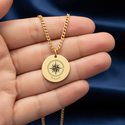 Compass rose coin pendant held in a hand