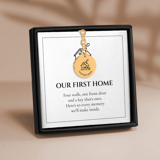 Our First Home coin keychain on its message card in a gift box