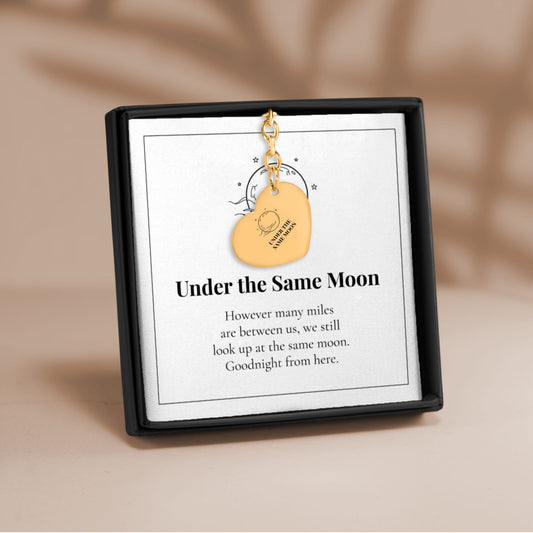 Under the Same Moon heart keychain in gold on its printed message card in a black gift box