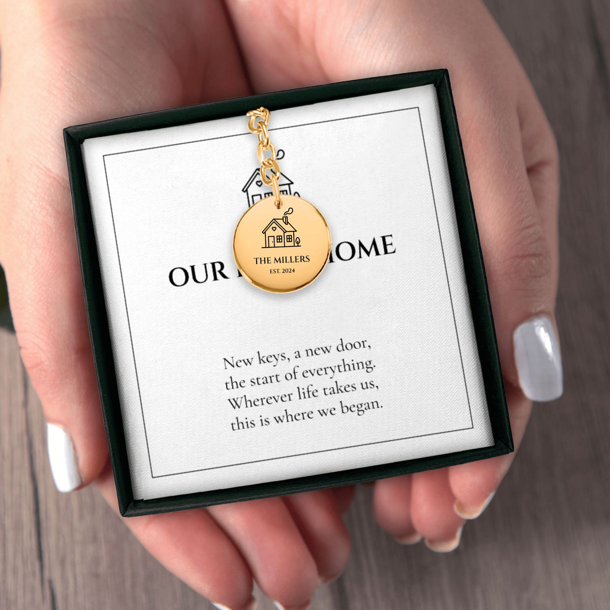 Hands holding the OUR FIRST HOME keychain gift box