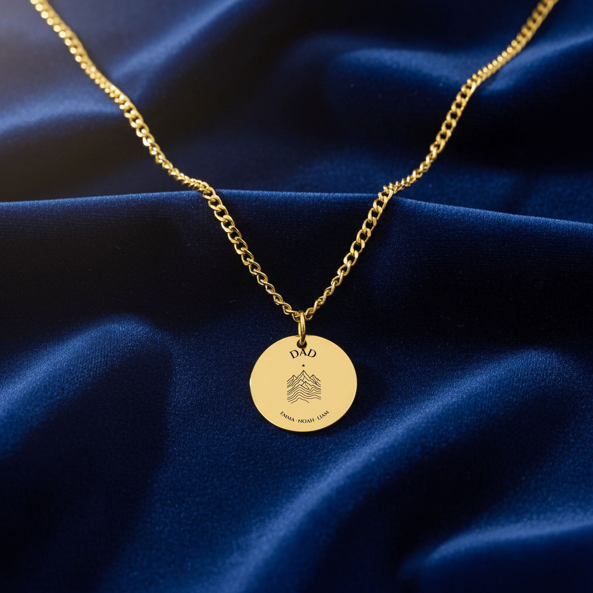 Gold Dad coin necklace on a Cuban curb chain on navy velvet