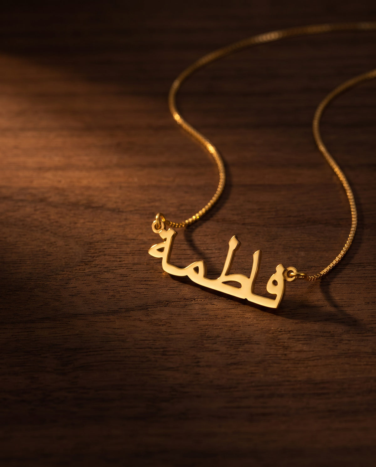 Gold Arabic name necklace on dark walnut