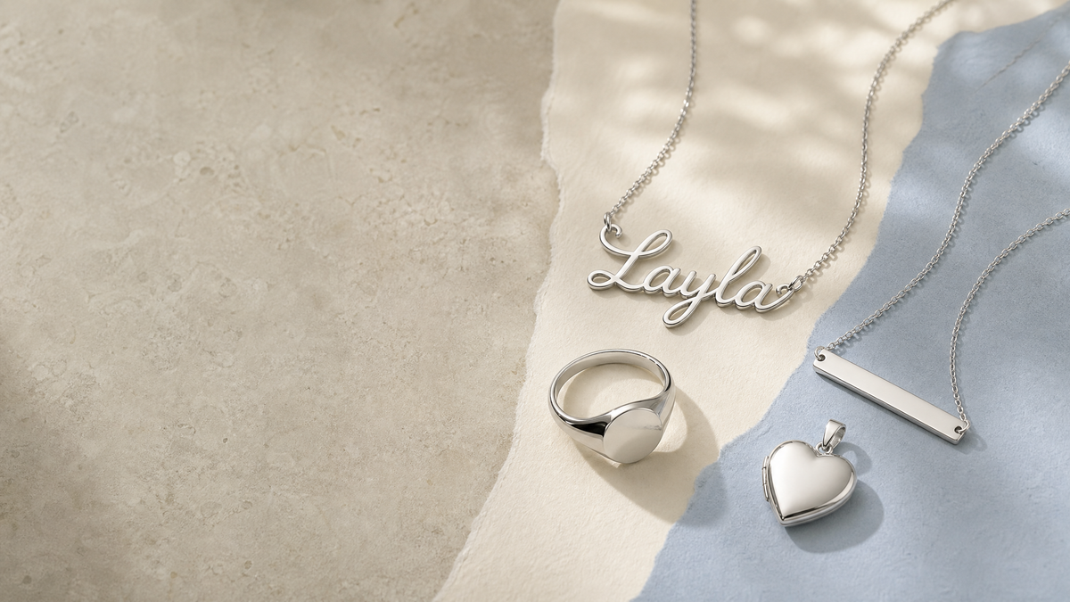 Silver name necklace, bar necklace, signet ring and heart locket on layered paper
